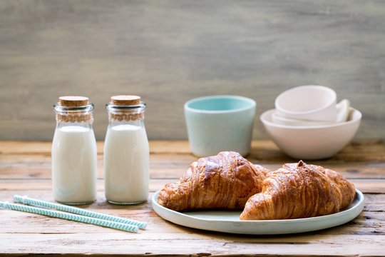 Delicious breakfast with fresh croissants and milk on old wooden background