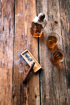 Whisky with ice and cigar on wooden table