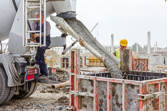 Zrenjanin, Vojvodina, Serbia - May 21, 2015: Workers at building site are pouring concrete in mold from mixer truck. Pouring reinforced concrete in foundation mold