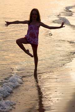 Happy girl dancing on the beach at the sunset time