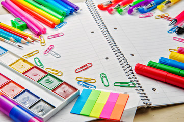 Notebook with school supplies on a wooden background