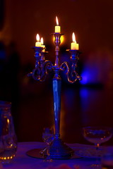 silver chandelier and burning candles on decorated wedding table.