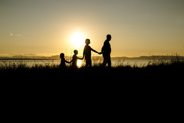 Fototapeta na wymiar family of four at sunset shadow black backlit