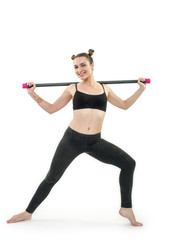 Young brunette woman doing pilates exercises with gymnastic stick isolated