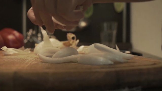 Female hands prepare onion on a wooden cooking board