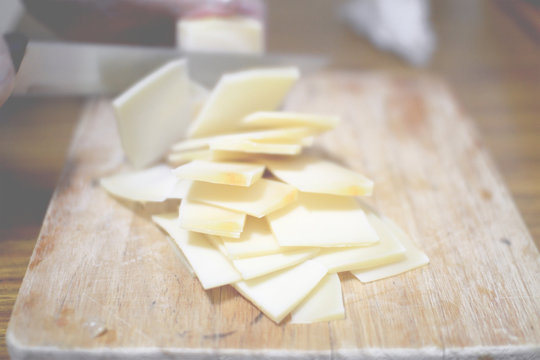 Slicing some cheese on a wooden table in a rustic kitchen.