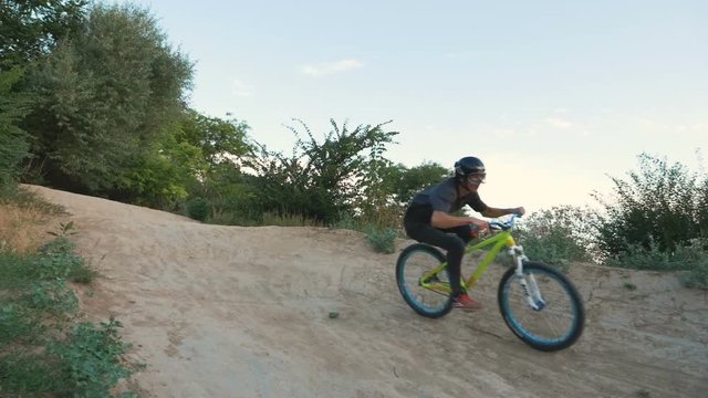 A mountain biker riding and jumping on track downhill at sunrise, slow motion