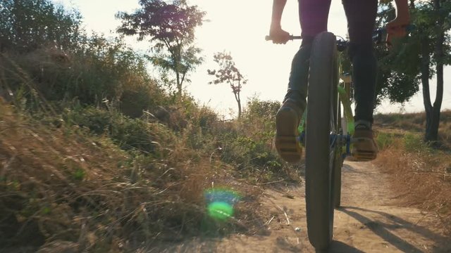A mountain biker riding on path at sunrise or sunset, slow motion, following