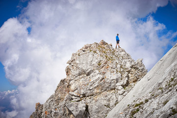 man reaching peak / standing on top of mountain