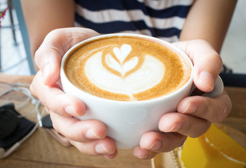 Woman holding hot cup of coffee, with heart shape