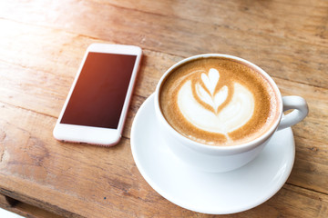 Cup of coffee and smart phone on wooden table