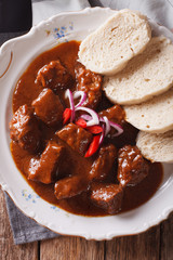 Thick goulash with dumplings on a plate close-up. vertical top view
