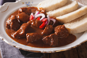 A thick stew with boiled dumplings on a plate close-up. Horizontal
