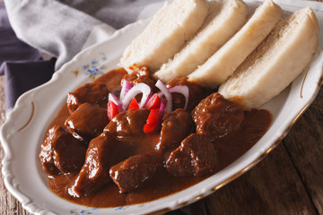 Thick goulash with dumplings on a plate close-up. horizontal
