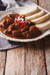Czech Food: goulash with knedle on the table close-up. vertical
