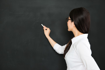 A good asian teacher writing on blackboard with chalk