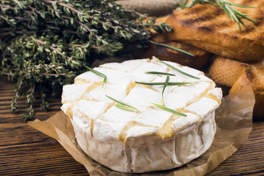 Camembert cheese with thyme and toasted bread on a wooden board