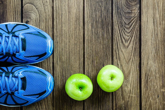 Sport shoes and apples  on a  wooden background. Sport equipment