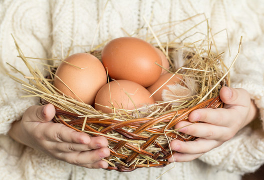 Wicker basket with chicken eggs in the children's hands