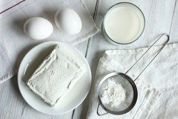 Cottage cheese, eggs and glass of milk on a white wooden table. Monochrome