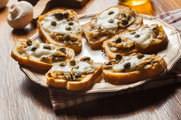 Crostini with fried mushrooms, onion and mozzarella cheese
