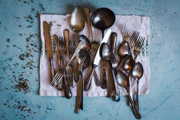 Old silverware on a linen embroidery cloth over turquoise stone table with pepper spice.