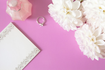 Paper for notes, perfume, ring, chrysanthemum on pink background