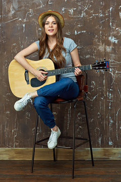 Young woman play music on acoustic guitar.