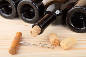 Corkscrew, corks and four bottles of wine. Selective focus