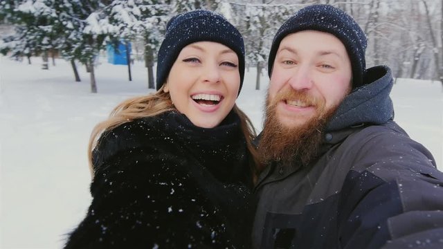 Young man and woman doing selfie in the winter forest and park