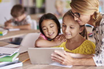 Teacher helping pupils with digital tablet