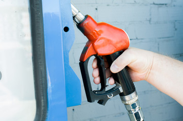a man at a gas station fills the fuel in the vehicle tank
