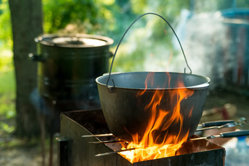 Cooking in sooty cauldron on campfire at forest