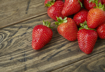 A pile of fresh home grown strawberries on a rustic table top background forming a page border
