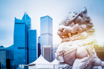 modern skyscrapers with a majestic stone lion in the foreground,hong kong,china. - obrazy, fototapety, plakaty