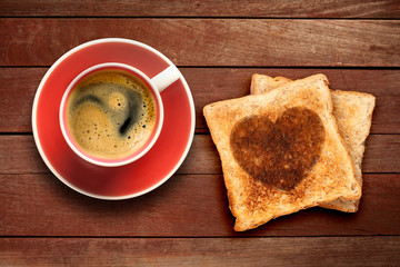 Breakfast, coffee and toast with a heart pattern, on a wood background