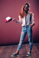 Sexy hip-hop woman in cap with long red hair. Fashion portrait of modern girl in cap