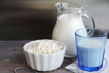 Fresh cottage cheese and milk on wooden kitchen table. Closeup.