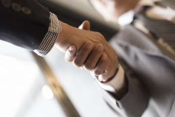businessmen in suit shaking hands beside window - business teamw