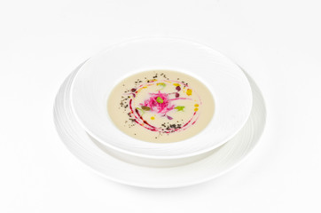 Cream soup of cauliflower with beetroot and truffle oil on a plate on a white background