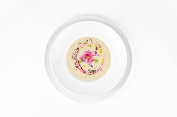Cream soup of cauliflower with beetroot and truffle oil on a plate on a white background, top view