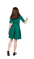back view of woman. Young woman presses down on something. Isolated over white background. Rear view people collection. backside view of person. The slender brunette in a green short dress is calling