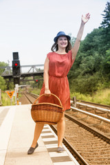 young woman standing at train station and waving to somebody