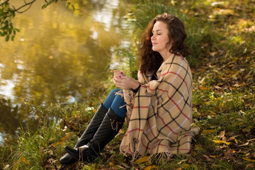 Young woman with blanket in the park in the autumn