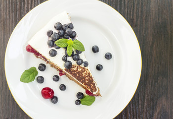 Piece of sweet cake with cherry, blueberry and mint