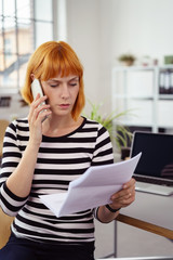 frau im büro schaut wütend auf einen brief und telefoniert
