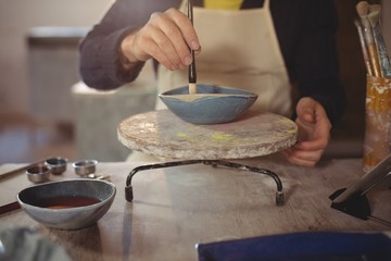 Fototapeta na wymiar Male potter painting on bowl