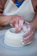 Mid section of female potter making pot