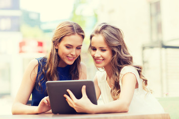 happy young women with tablet pc at outdoor cafe