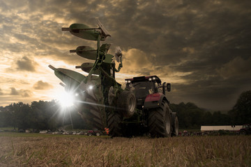 Traktor fährt über ein Feld bei Sonnenuntergang